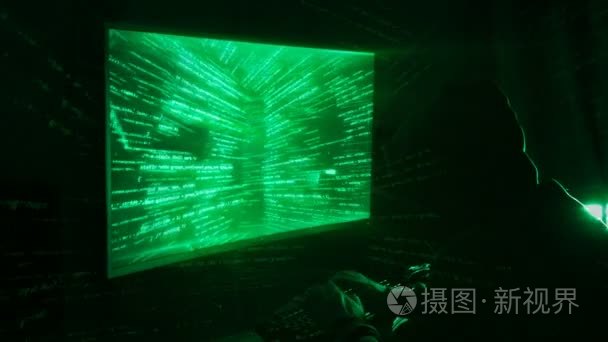 一个人黑客在一个黑暗的房间里的敞篷工作与程序代码