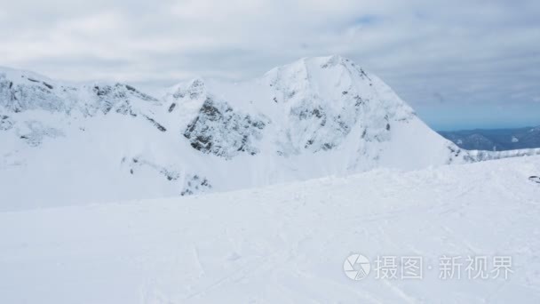 一个穿着鲜艳西装的滑雪者来到山顶  看雪山  4k。