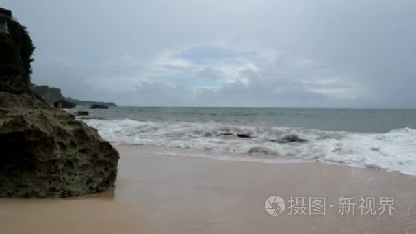 印尼巴厘岛的大雨中, 海滩上的年轻女子穿着黄色的雨衣