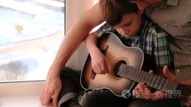 演奏乐器。爸爸教儿吉他, 坐在窗台上。