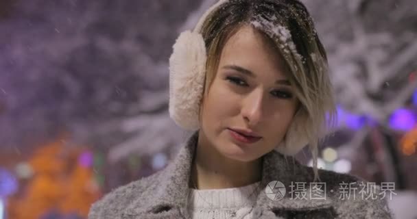 都市情感肖像年轻美丽的女孩在冬夜城  女人看着相机。女士穿着时尚经典的冬季针织服装。雪花飞扬
