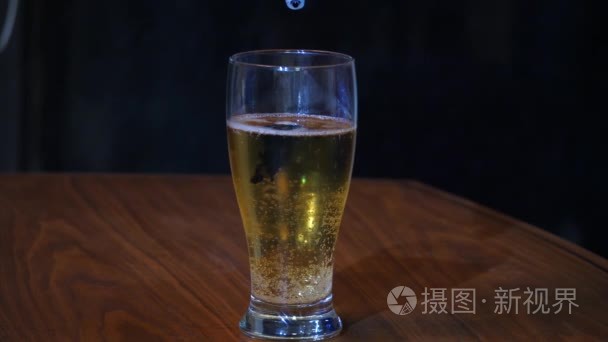 创建一品脱蓝色啤酒泡沫白头使用食品着色庆祝坐在一个黑色的木纹表和黑色背景