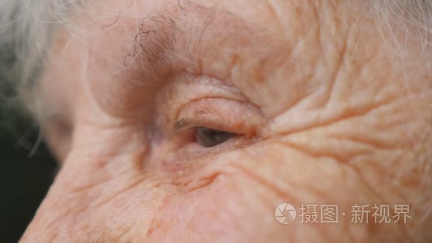 关闭老妇人的画像看着。在他们周围有皱纹的老太太的眼睛。侧面视图慢动作