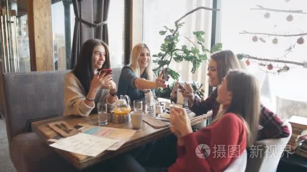 四美丽的妇女坐在咖啡馆与电话视频