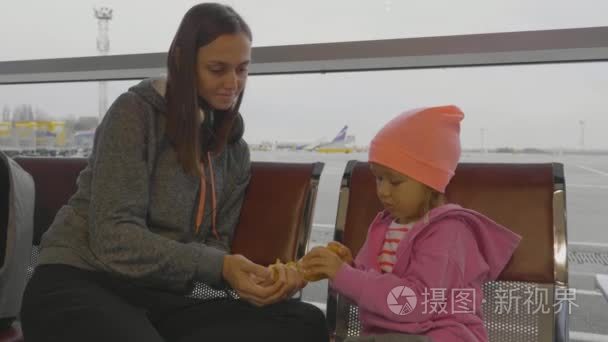 母亲和女儿在机场。小女孩在候诊厅打扫普通话