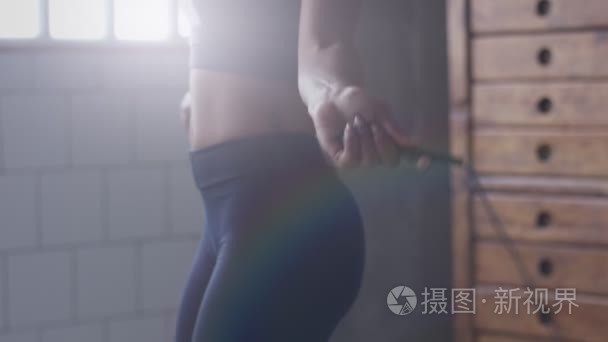 混杂的种族妇女在跳跃的绳索锻炼期间在阳光阁楼