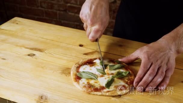 厨师用刀子把现成的比萨饼切成块。4k