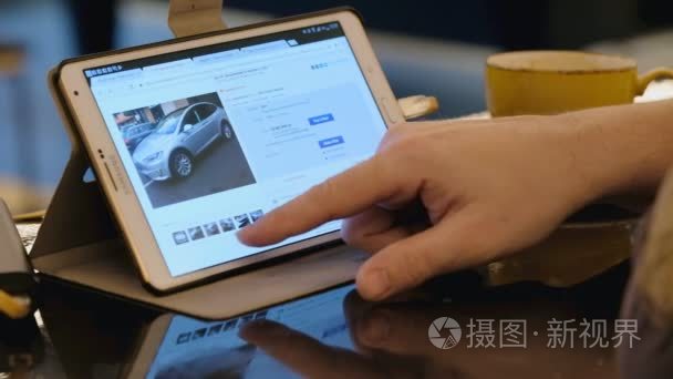 人探索易趣网站寻找二手特斯拉汽车使用平板电脑在咖啡馆