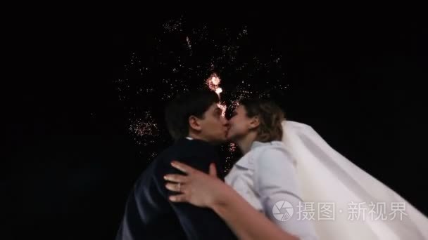 在烟花背景下亲吻新婚夫妇特写肖像