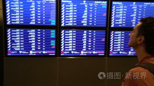 在机场候机楼国际航班商人出国旅游的概念上看时刻表板屏幕的男士乘客