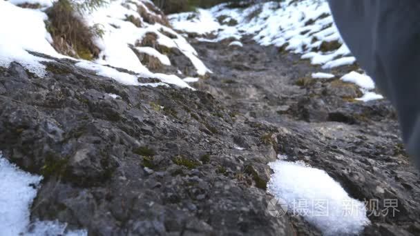 脚的不被辨认的家伙爬上在山上的踪迹在早上。在雪山上漫步的年轻男性游客。健康的积极生活方式。假期或假期的概念。后向后视图慢动作