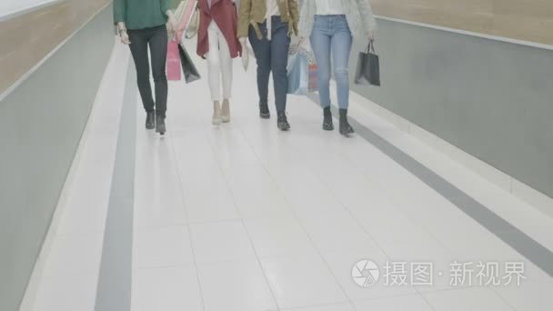 女性穿着不同的服装风格和鞋子走在商场举行购物袋