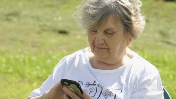 成熟的老年妇女举着手机在户外视频