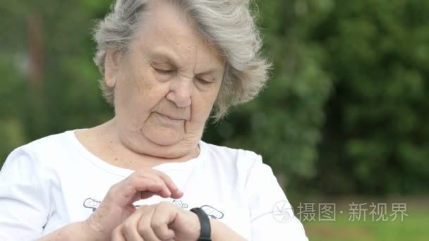 老年妇女看腕带健身追踪器视频