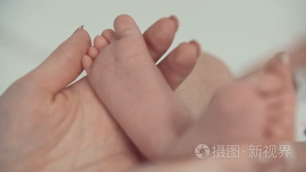 新生儿婴儿脚在母心形手上。妈妈和她的孩子