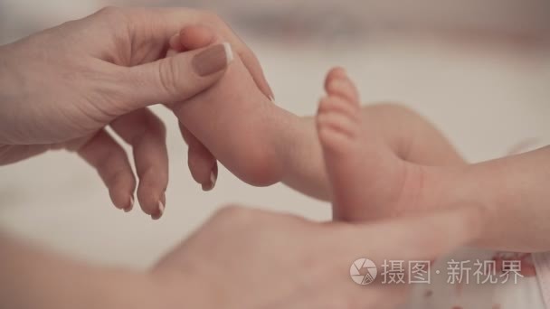 新生儿婴儿脚在母心形手上。妈妈和她的孩子