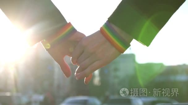 在街道的背景下, 两只手用 Lgbt 手镯互相伸展。