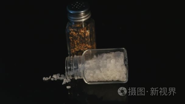 黑后台玻璃罐中的海盐和黑胡椒视频