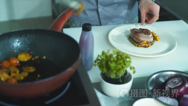厨师把蔬菜放在一盘肉上。