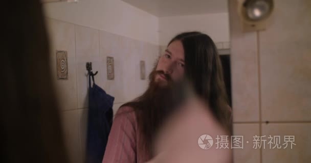 一个年轻的大胡子男子梳理他的长发