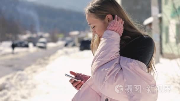 女性使用智能手机在冬季城市街慢动作