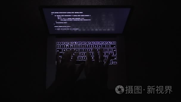 在黑暗中键入笔记本电脑的人的最高视图