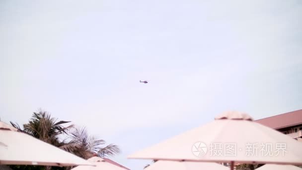沙滩上的雨伞  高高的天空中飞着一架直升飞机