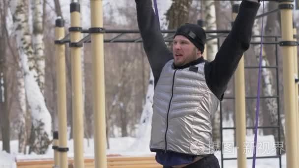 男健美运动员在冬季公园操场上做蹲运动