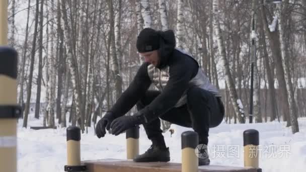 青年男子跳上板凳在冬季公园 crossfit 训练室外