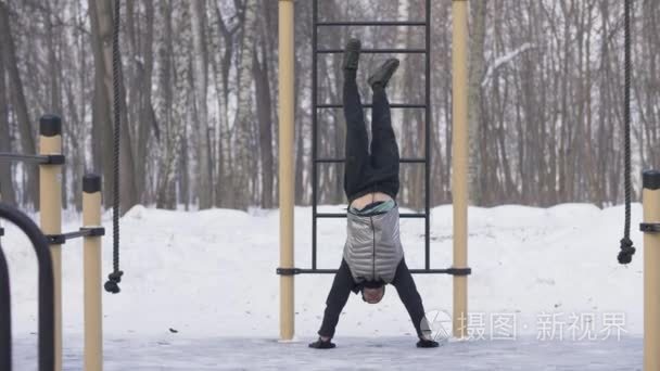 男子训练推 ups 运动与腿在冬季运动场上上升