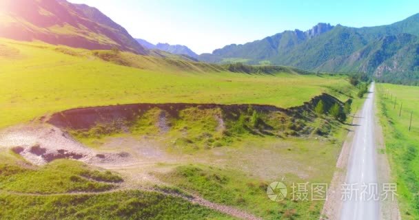 在晴朗的夏日清晨  空中的乡村山路和草地。沥青公路与河道