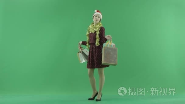 一个年轻的女孩显示圣诞购物的结果在绿色屏幕上的观众视频