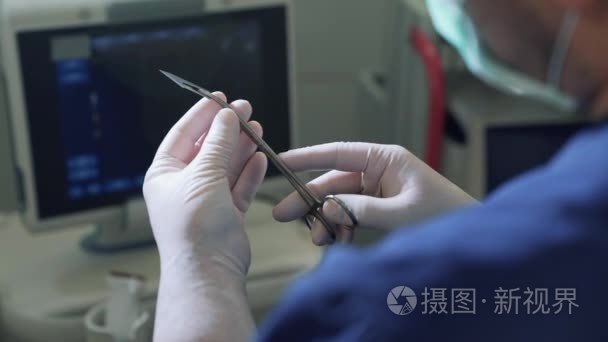 从个人角度看, 医生在无菌手套的手术前持有手术刀刀片的钳位.