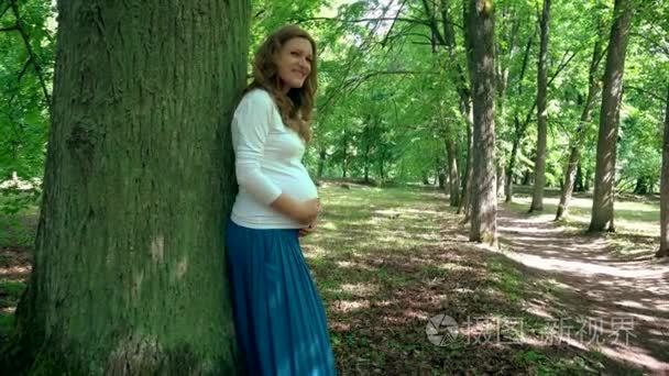 月怀孕妇女在公园树干附近放松视频
