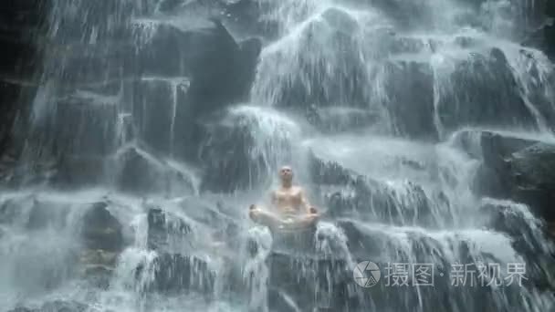 男子坐在瑜伽姿势在背景瀑布视频