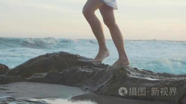 脚在岩石海滩上行走。腿通过在 se 海岸的石头