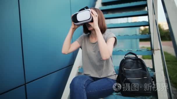 未来是现在。美丽的年轻女性在楼梯上玩游戏或看电影的 vr 眼镜。年轻的白种女人触摸的东西使用现代虚拟现实玻璃在蓝色背景视频