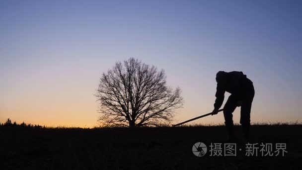 工人的剪影在晚上铲土用铁锹视频