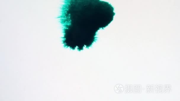 绿色墨水在白色表面流动。墨滴下降  并蔓延到质感的白皮书  特写视图。视频和动画图形模板