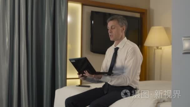 在酒店房间里聊天的商人通过笔记本电脑