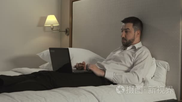 在床上使用笔记本电脑的商人