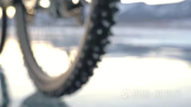 轮胎的看法。射击180fps。女人在冰上骑自行车。冰冻的贝加尔湖的冰。自行车上的轮胎布满了特殊的尖峰。