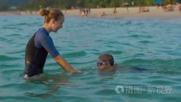 女子游泳指导员教小男孩在海里游泳 sundet