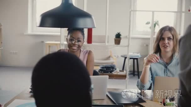 年轻快乐美丽的多民族女性同事在时尚的阁楼 coworking 空间4k 的办公餐桌洽谈业务