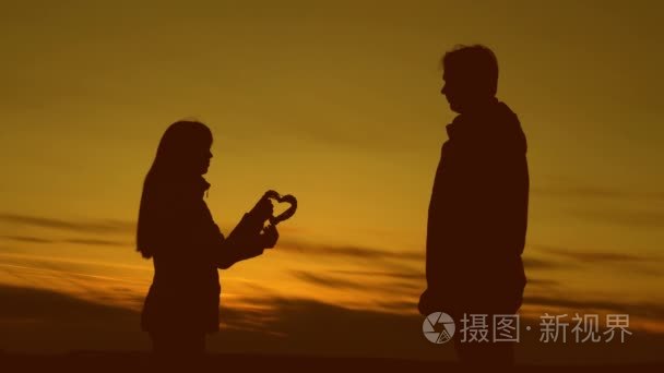 男人和女人在日落时抱着爱的心