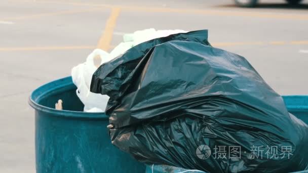 一个老妇人在垃圾桶里扔出满满一包垃圾.短视频