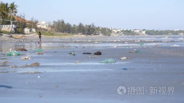 被垃圾和垃圾污染的海滩上对孩子进行散焦射击的镜头