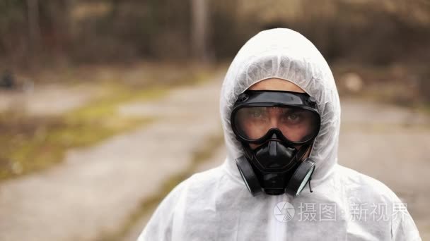 人在生物危险西装和防毒面具看直接入照相机