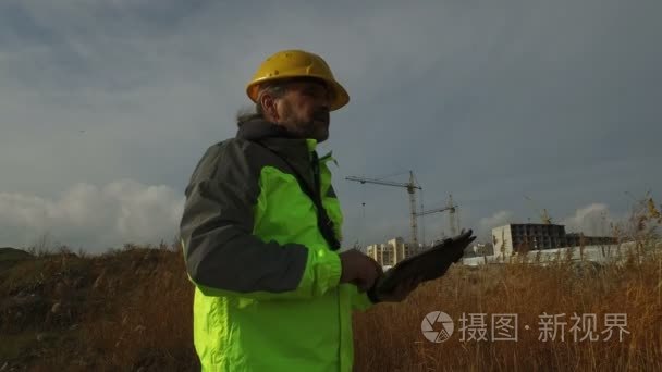 在建筑背景下使用平板头盔的成熟男职工工头