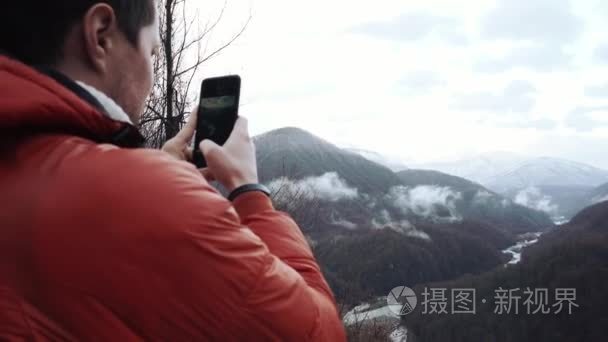 成人游客在冬季夹克拍摄美丽的山景观图片